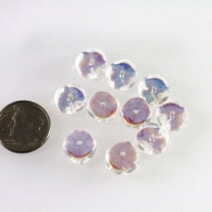 Several round, clear acrylic beads with an iridescent purple and blue finish, displayed on a white surface next to a dark coin for scale.