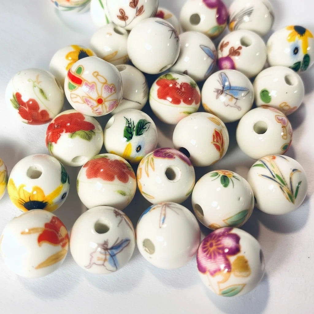A pile of round white ceramic beads with colorful hand-painted floral and butterfly designs, with a US dime coin in the center for scale.