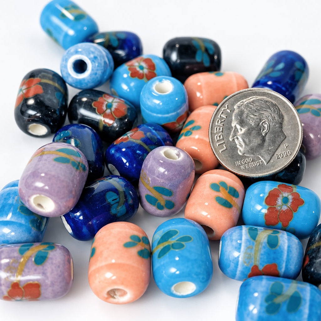 A pile of colorful glass lampwork beads with floral patterns in blue, purple, orange, and black, with a US quarter coin in the center for scale, on a white background.