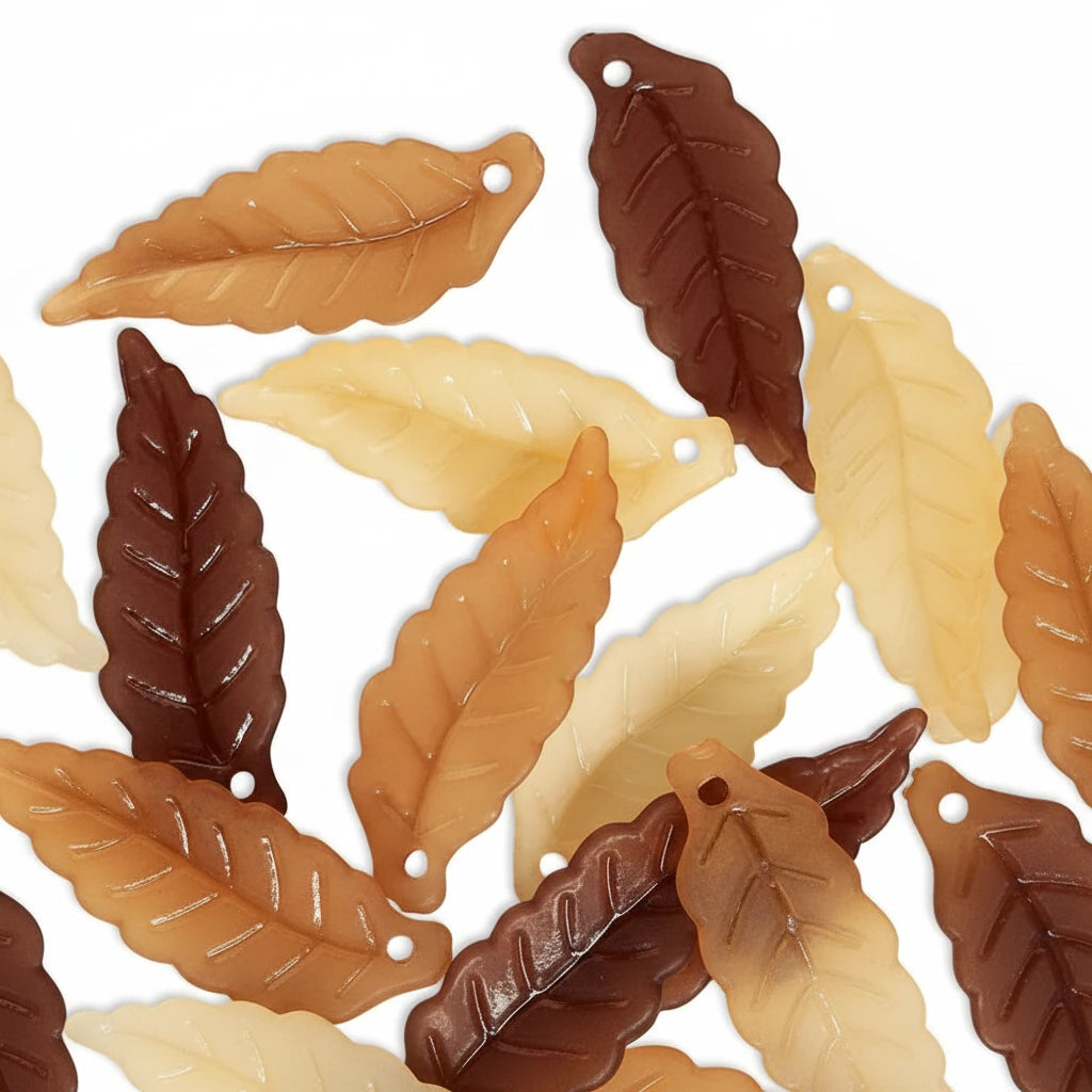 Multiple leaf-shaped jewelry charms in cream, tan, and dark brown, arranged on a plain white background.