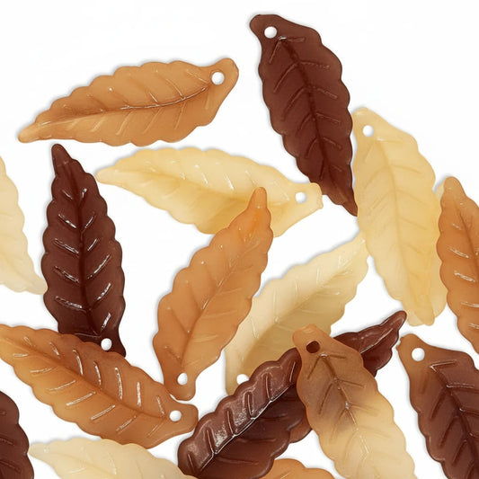 Multiple leaf-shaped jewelry charms in cream, tan, and dark brown, arranged on a plain white background.