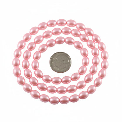 A strand of pink oval pearl beads displayed on a white background, with a US quarter coin and a millimeter ruler included for scale.