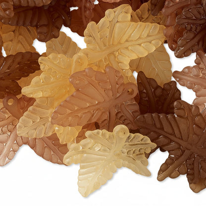A pile of translucent leaf-shaped beads in autumn shades of amber, tan, brown, and deep burgundy, shown on a white background.