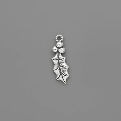 A small silver holly leaf charm with three berries and a top loop, shown on a solid dark gray background.