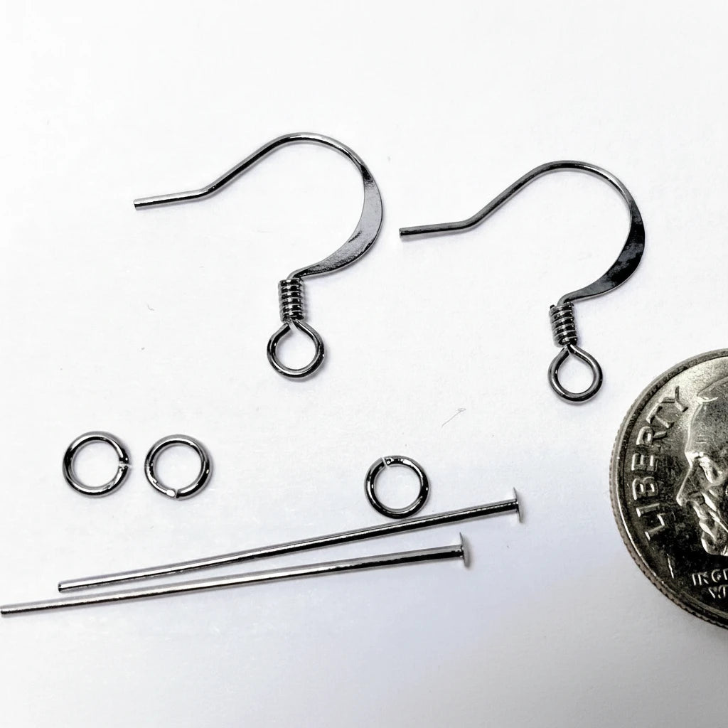 Silver metal jewelry findings including two ear hooks, two jump rings, two short spring rings, and two long wire loops, shown on a white background with a US quarter coin for scale.