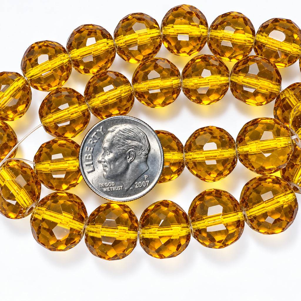 Faceted amber glass beads on a clear string, shown with a US dime for scale on a white background.