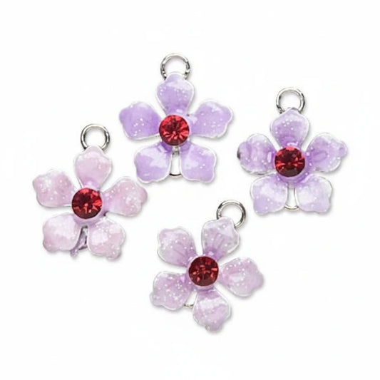 Four glittery flower-shaped jewelry charms in light purple and pale pink, each with a red faceted crystal center and a silver metal loop at the top, arranged on a plain white background.