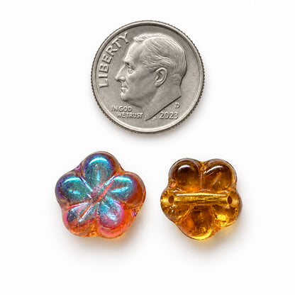 Two small flower-shaped glass beads shown next to a U.S.