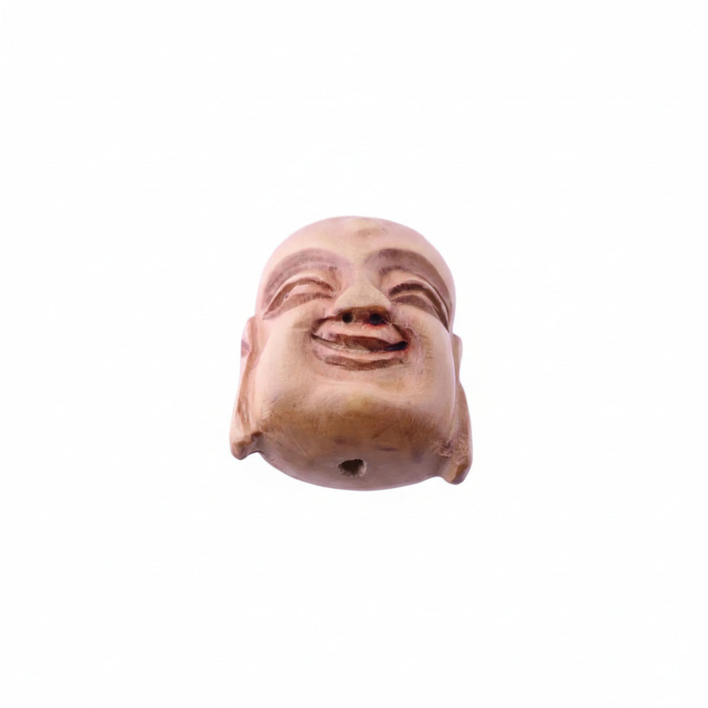 A carved wooden Buddha head sculpture with a smiling expression, featuring a small hole at the bottom, set against a plain light background.