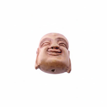 A carved wooden Buddha head sculpture with a smiling expression, featuring a small hole at the bottom, set against a plain light background.