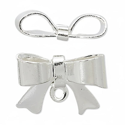 A pair of silver bow charms, one flat and one with a hanging loop, shown on a plain white background.
