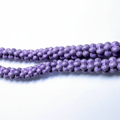 Purple textured stone beads with a unique knotted or looped shape, arranged in strands on a plain white background.