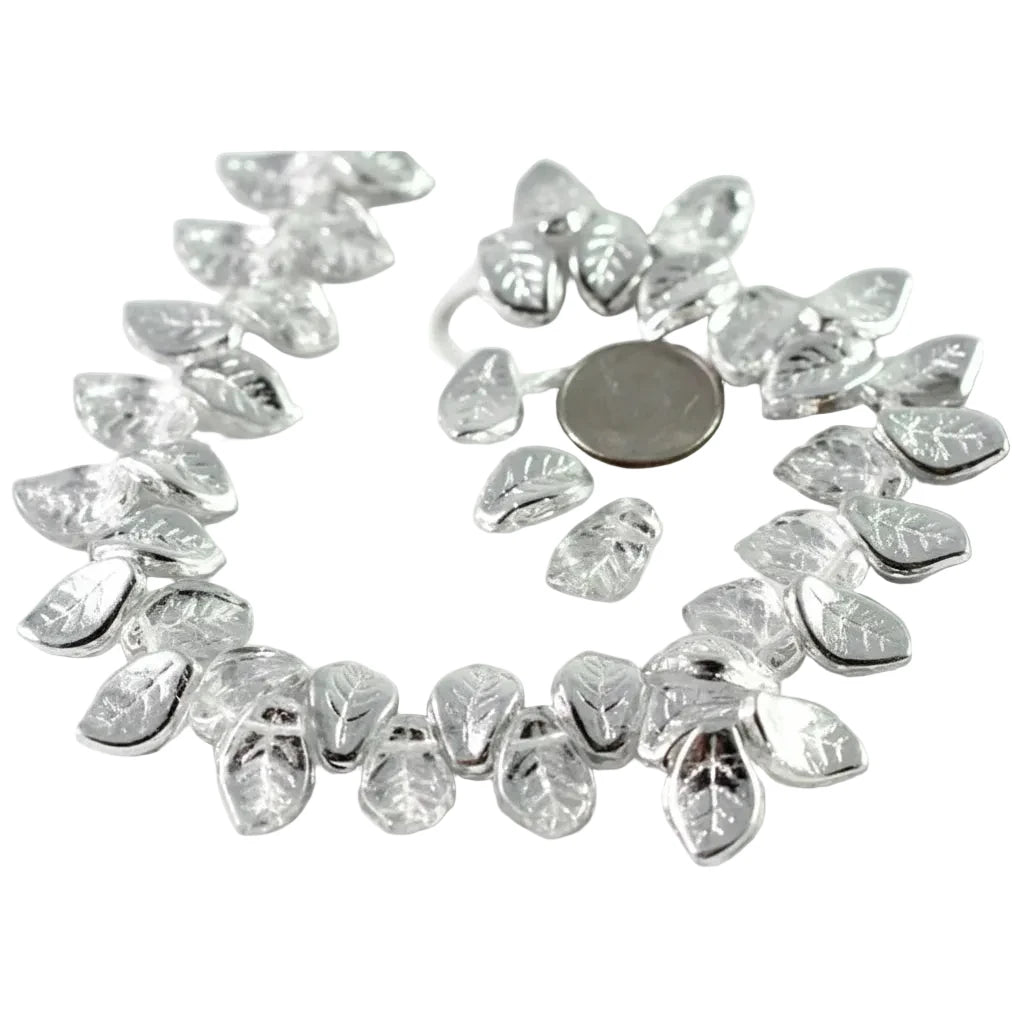 A strand of silver-toned leaf-shaped beads with clear faceted centers, arranged in a circle on a white background with a coin for scale.