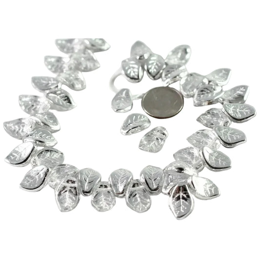 A strand of silver-toned leaf-shaped beads with clear faceted centers, arranged in a circle on a white background with a coin for scale.