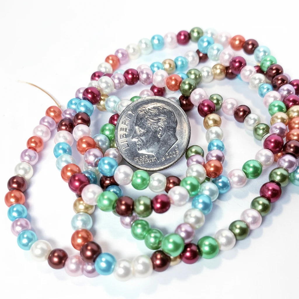 Multicolor faux pearl bead strands coiled around a silver US dime for scale, on a white background.