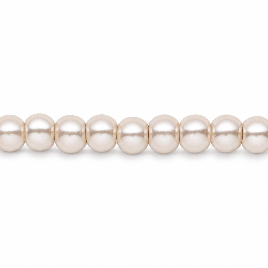 A close-up of a strand of round, lustrous pearl-like beads in a warm off-white or cream color, shown against a plain white background.