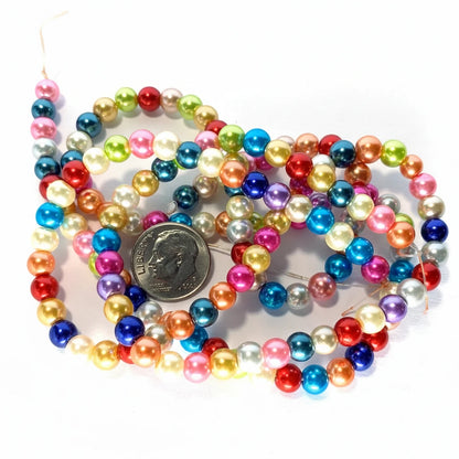 Multicolor glossy pearl beads on strands, shown with a US quarter coin for scale on a white background.