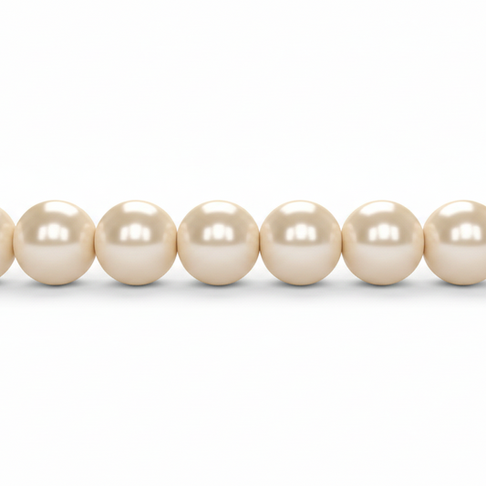 A close-up of a strand of round, lustrous pearl-like beads in a warm cream or ivory tone against a plain white background.