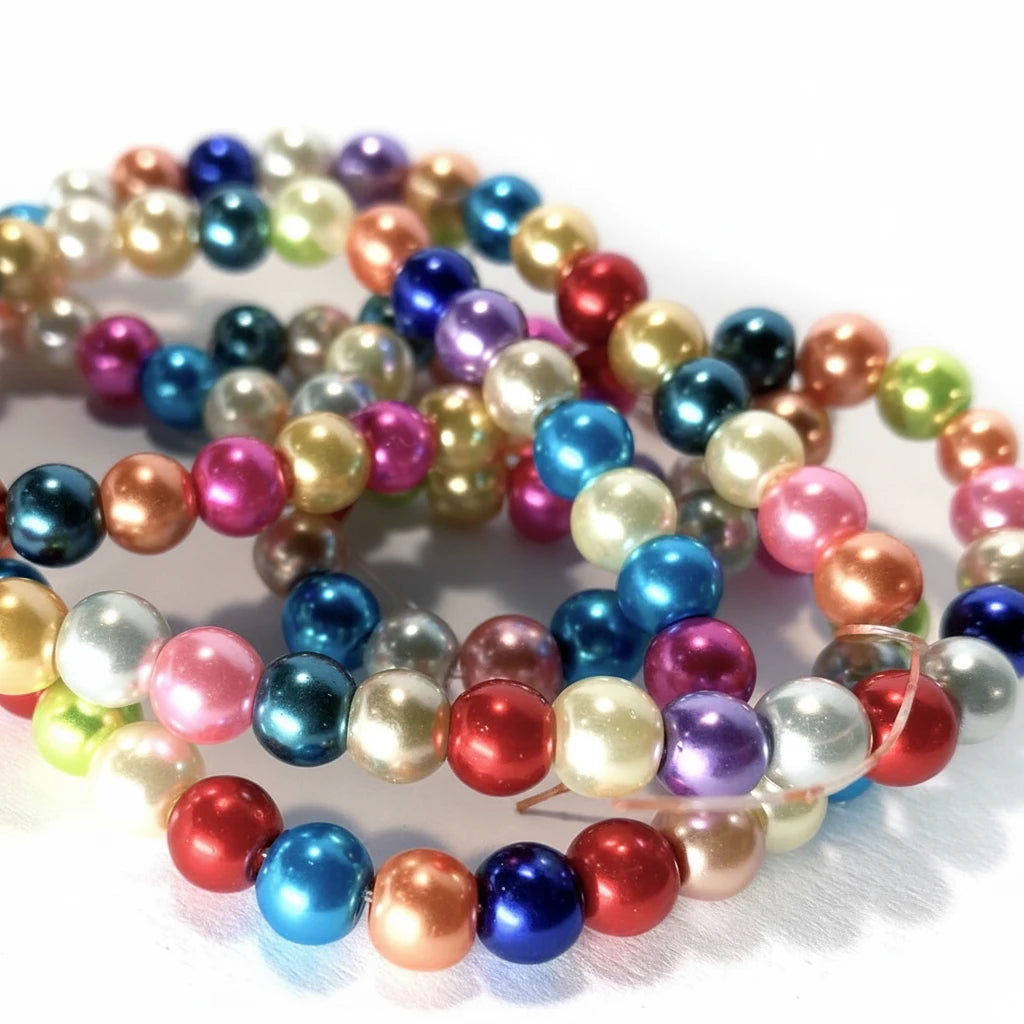 A close-up of multicolored faux pearl beads with a glossy, metallic finish, arranged in a spiral on a white surface.