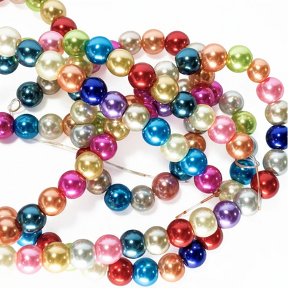 A pile of colorful round pearl beads on a white background, featuring a variety of vibrant colors including blue, pink, red, green, gold, and silver.