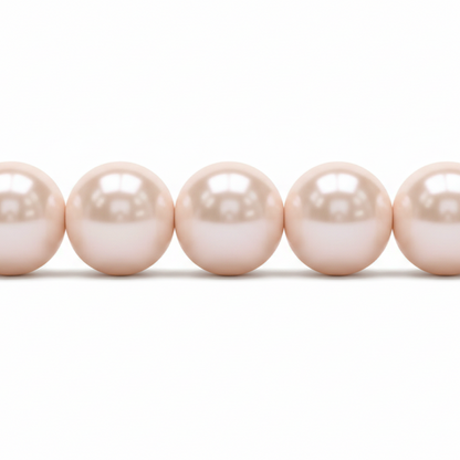 A close-up of a strand of round, lustrous pearl beads in a soft champagne-pink color, shown against a plain white background.