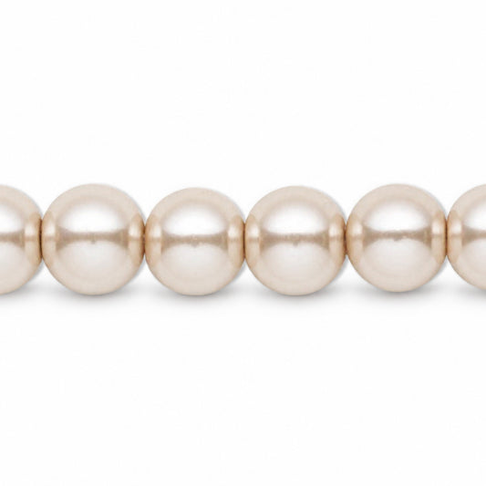 A close-up of a strand of round, lustrous pearl-like beads in a warm champagne or cream tone against a plain white background.