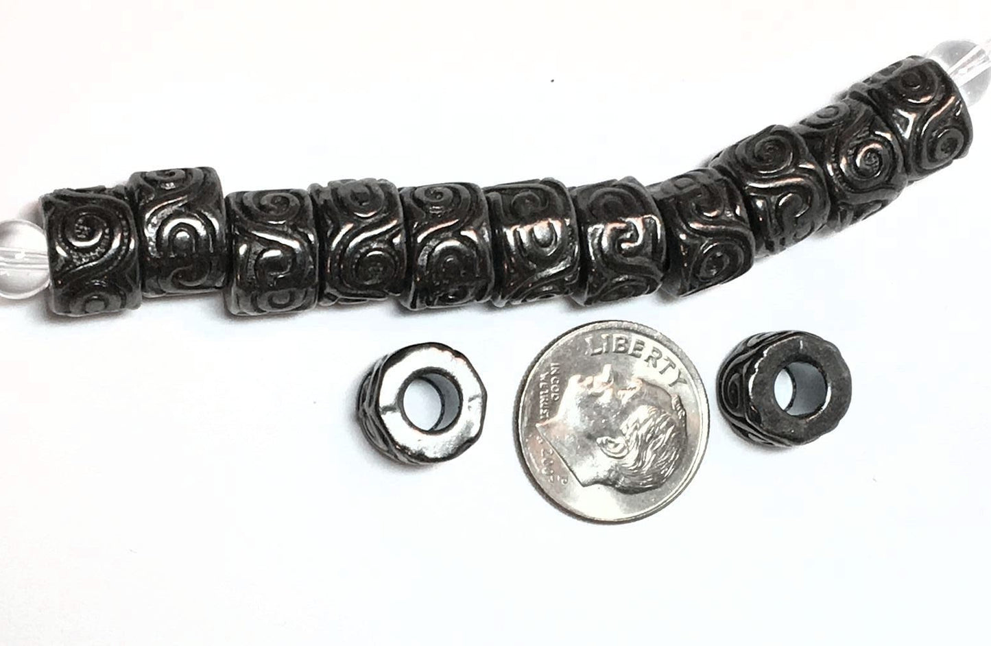 Decorative black bead with a silver bead, next to a dime for scale on a white background