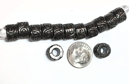 Decorative black bead with a silver bead, next to a dime for scale on a white background