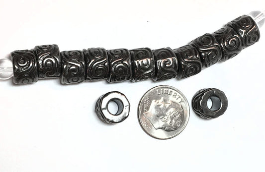 Decorative black bead with a silver bead, next to a dime for scale on a white background