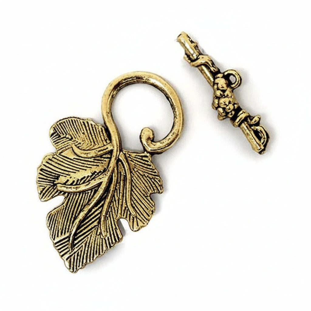An antique gold leaf-shaped pendant charm with a loop, shown next to its matching key-shaped clasp on a plain white background.