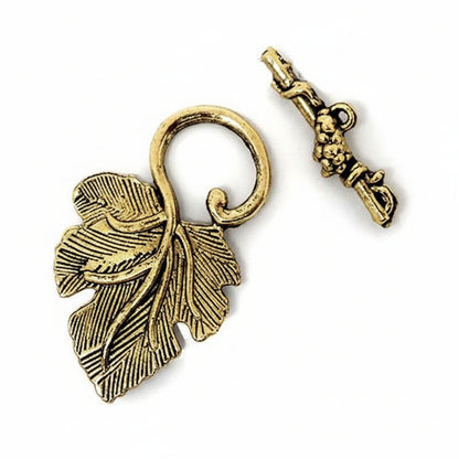 An antique gold leaf-shaped pendant charm with a loop, shown next to its matching key-shaped clasp on a plain white background.