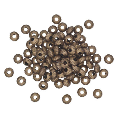A pile of small metallic spacer beads with a textured, ribbed outer edge and a central hole, shown on a plain white background.