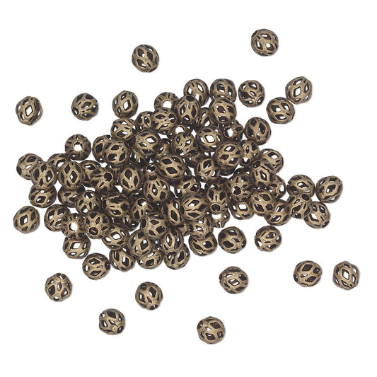 A pile of small metallic spacer beads with a bronze finish, scattered on a plain white background.