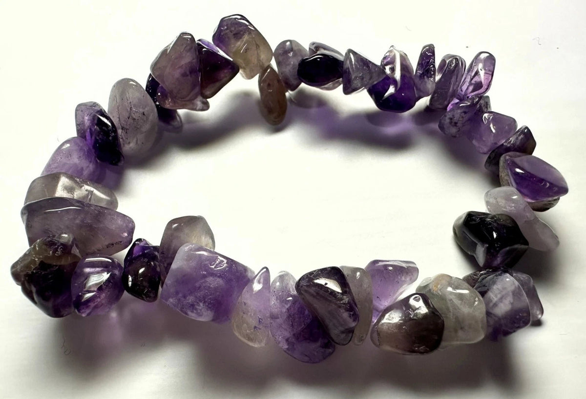 A beaded stretch bracelet made of irregular, polished purple amethyst gemstones in various shades of translucent violet, dark purple, and smoky gray, displayed on a plain white background.