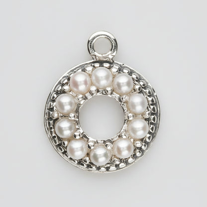 A sterling silver circular pendant charm featuring a halo of small white pearls around a central open circle, with a top loop for attachment, shown on a plain white background.