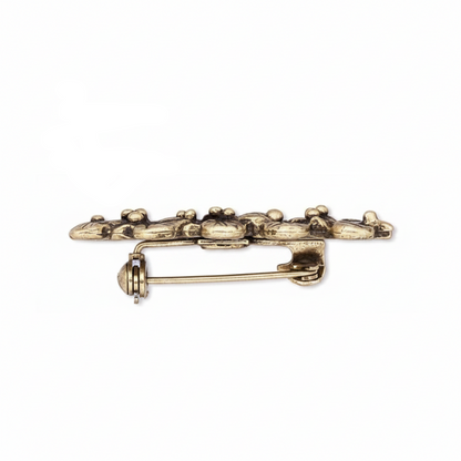 antique gold holly leaf and berry brooch pin on a plain white background, showing the front decorative side, the back with pin clasp, and the reverse side.