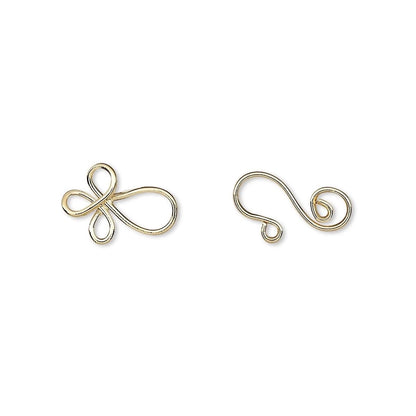 Two small gold metal wire findings, one shaped like a stylized infinity symbol and the other like a curled tail piece, shown on a plain white background.