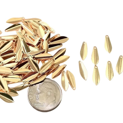 Gold metallic teardrop-shaped charms or beads scattered on a white background, with a U.S.