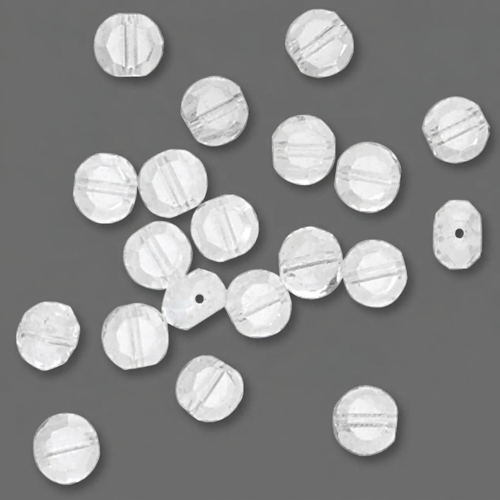 A scattered assortment of small, faceted white glass beads on a solid dark gray background.