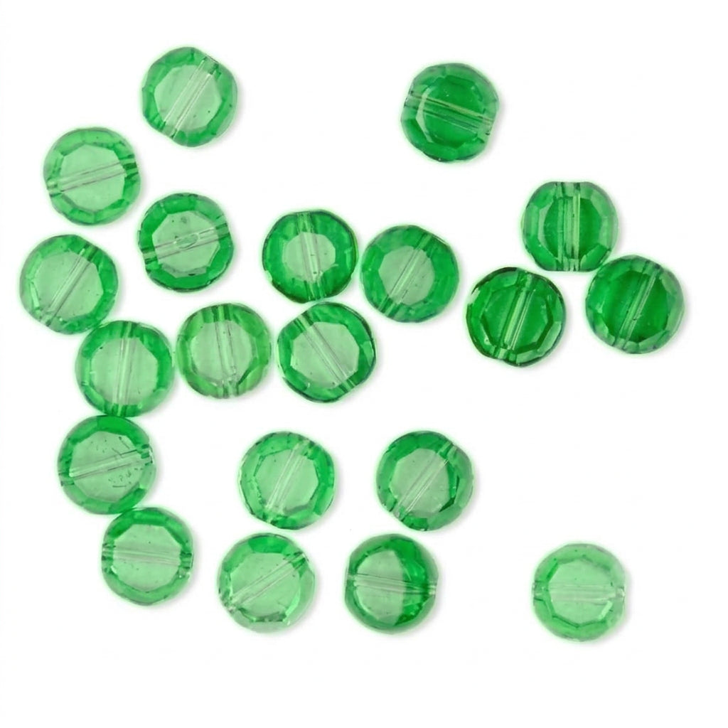 A group of small, round, transparent green beads with faceted edges scattered on a plain white background.