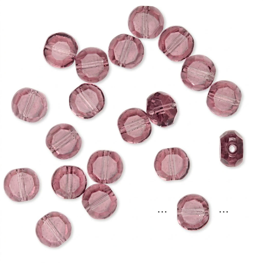 A set of faceted round beads in a dusty rose pink color, scattered on a plain white background.