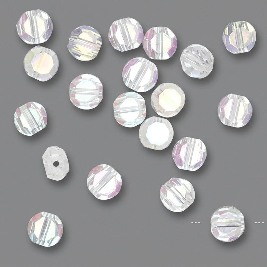 A set of round faceted crystal beads with a pearlescent iridescent finish, scattered on a solid dark gray background. 