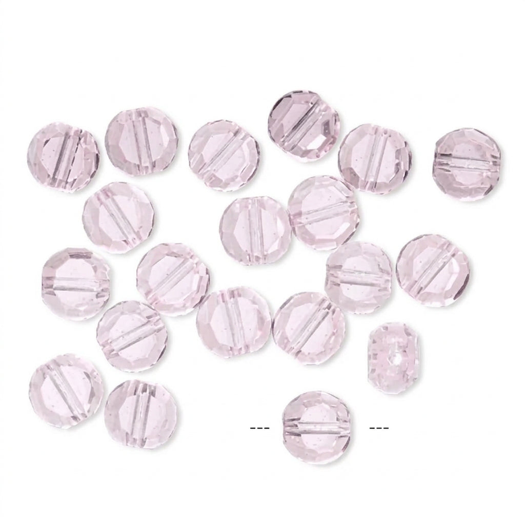 A group of light pink faceted round beads scattered on a plain white background.