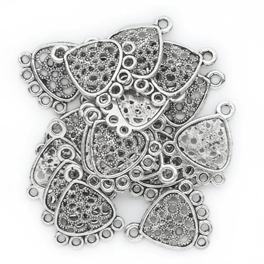 A pile of silver-toned filigree trapezoid charms with loop tops, shown on a plain white background.