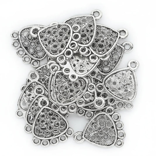A pile of silver-toned filigree trapezoid charms with loop tops, shown on a plain white background.