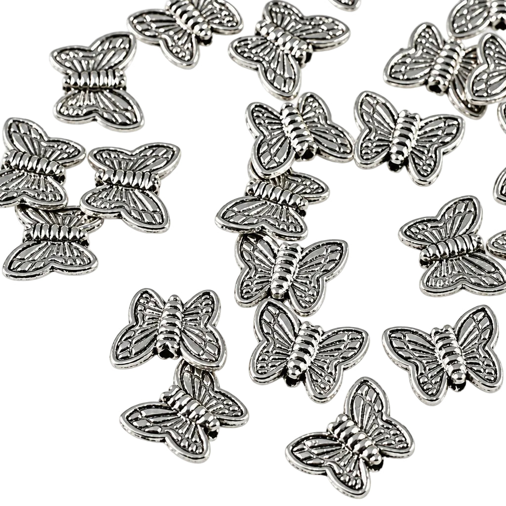 A pile of small silver butterfly-shaped charms or beads scattered on a plain white background.