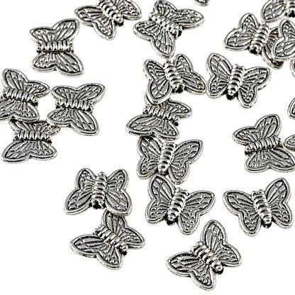A pile of small silver butterfly-shaped charms or beads scattered on a plain white background.
