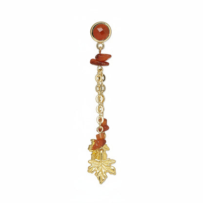 A pair of gold dangle earrings featuring faceted orange-red gemstone beads, small gold chain links, and dangling gold charms shaped like grapes and a leaf, set against a plain white background.