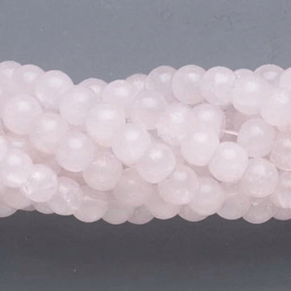 A close-up of pale pink translucent round beads strung together on a cord, set against a dark gray background.