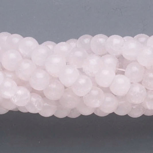 A close-up of pale pink translucent round beads strung together on a cord, set against a dark gray background.